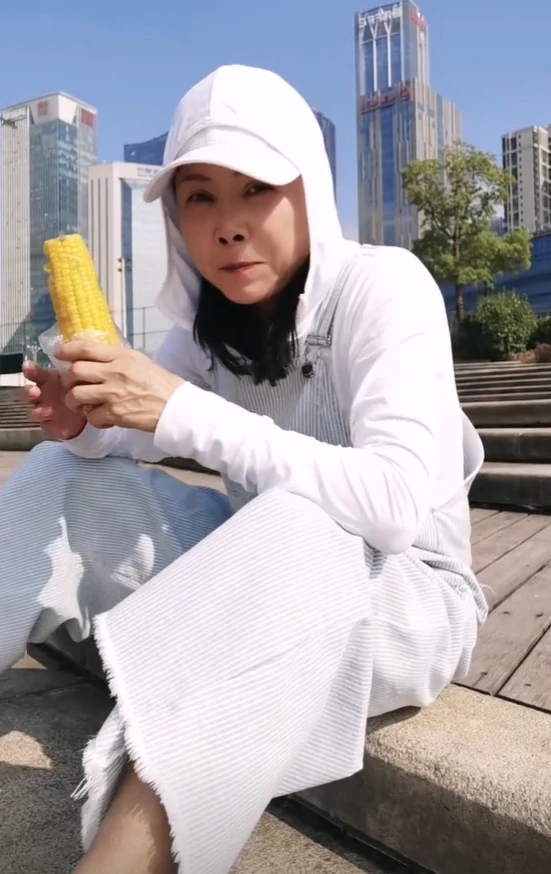 56岁的田震在街上吃玉米!用塑料袋嚼,穿白裤子,坐在地上不怕脏